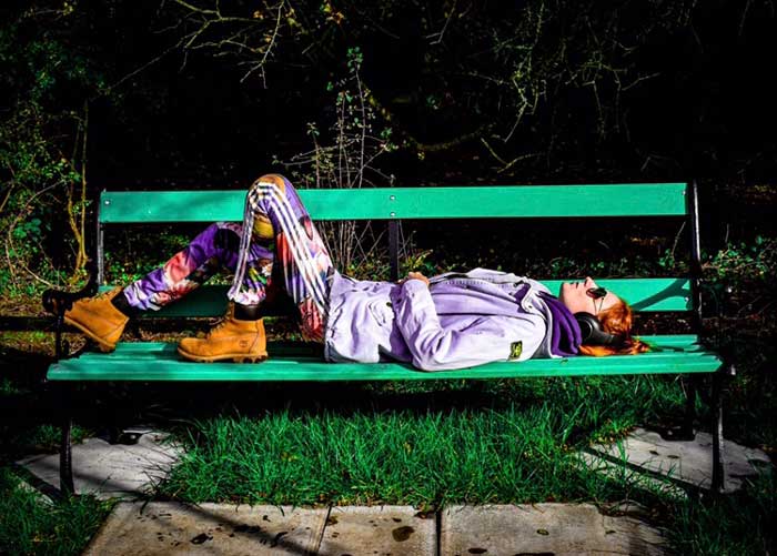 A young person lying on a bench listening to music