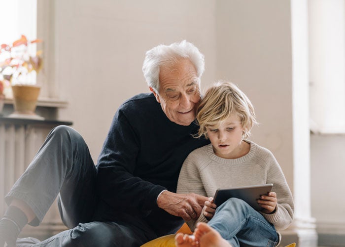 A grandfather and child looking at a tablet together