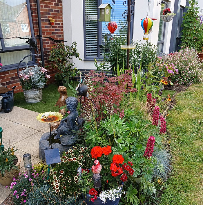 A pretty arrangement of garden ornaments, plants and flowers in a back garden