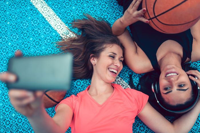 Two people laying on the ground looking at a mobile phone