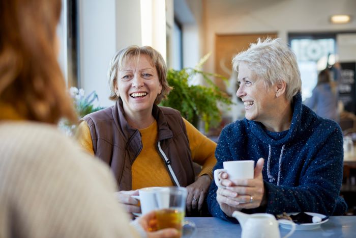 3 women sitting around a table drinking coffee