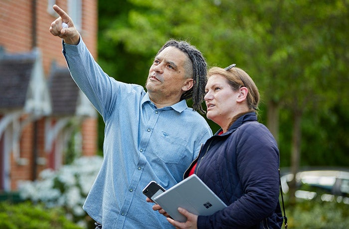 Two SNG employees standing outside a house checking the roof and gutters