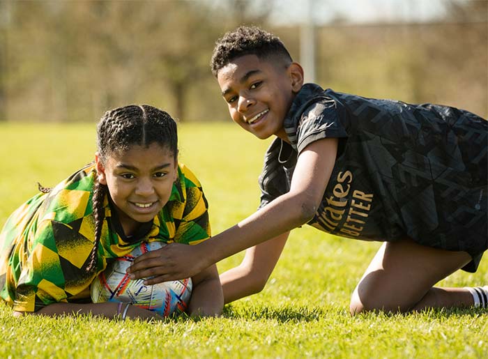 Two boys laying on grass with a football on a sunny day