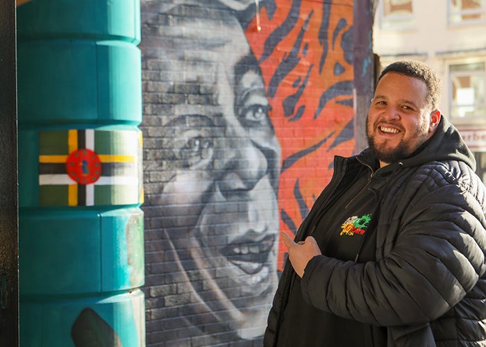Mark Daley is the son of Gullu, the man depicted in the mural behind him. Gullu was a musician and much-loved member of the Bristol community.