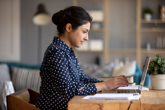 A woman sitting at a desk in her home working on her laptop