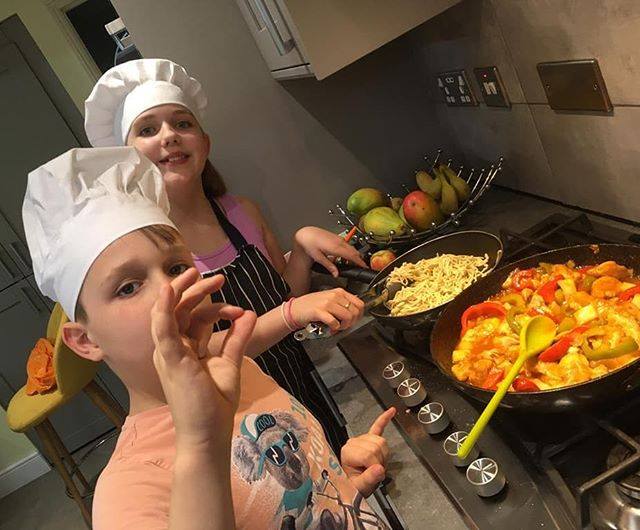 Two children wearing chefs hats cooking a healthy meal