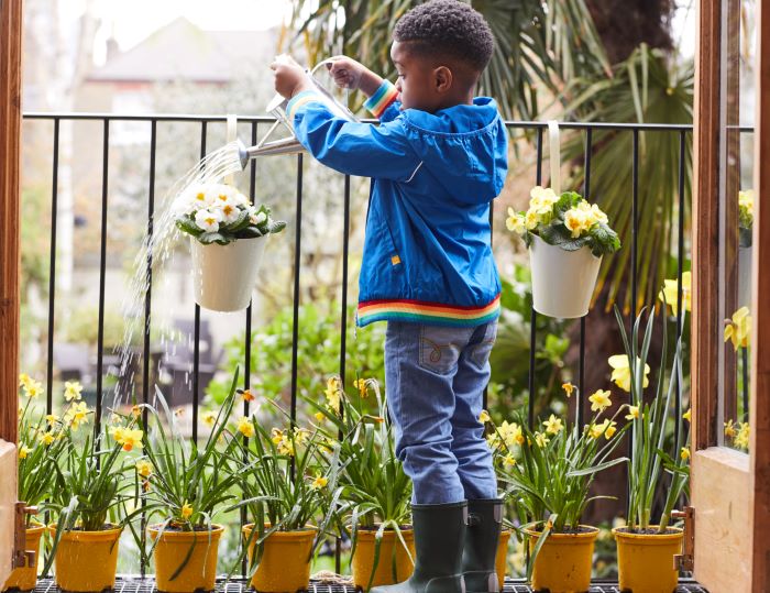 A young boy watering plants. 