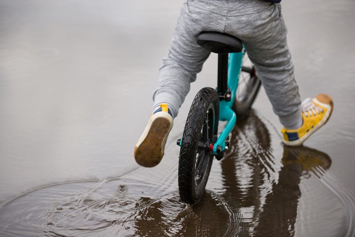 Young child on a bike riding through a puddle