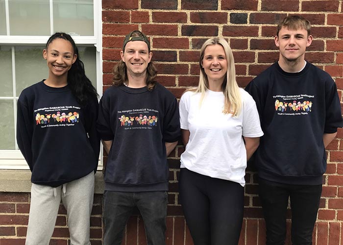 Four young people standing against a wall