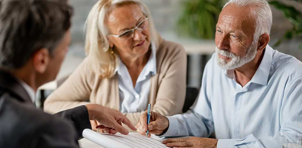Elderly man and woman signing financial documents