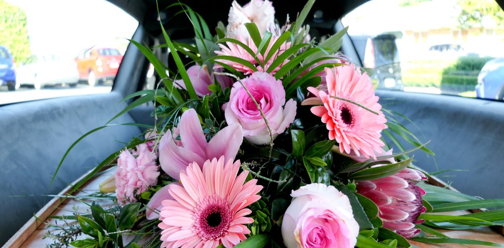 Pink funeral flowers sitting within a hearse
