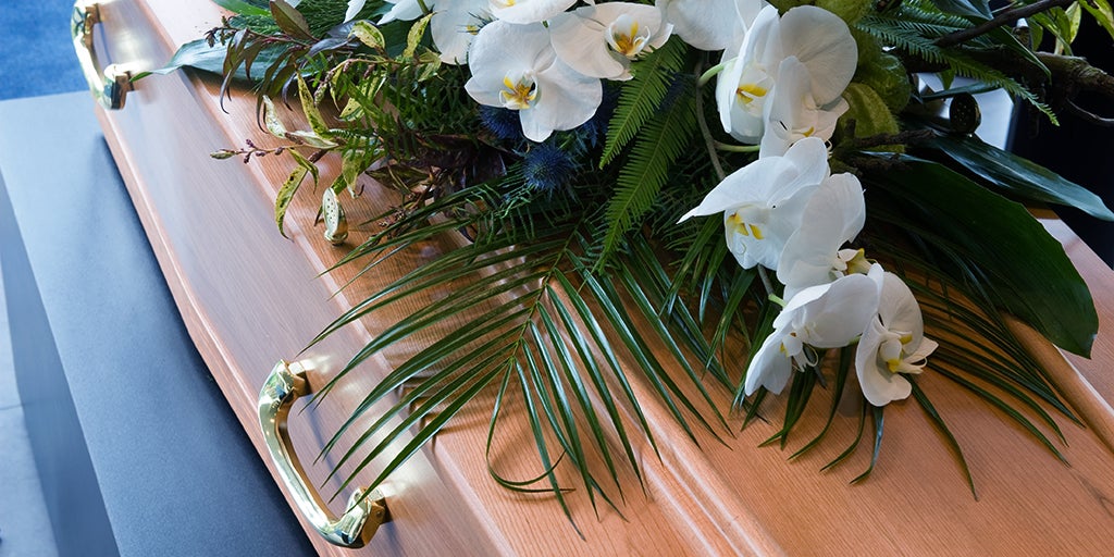 Closed coffin with white lily flowers sitting on top
