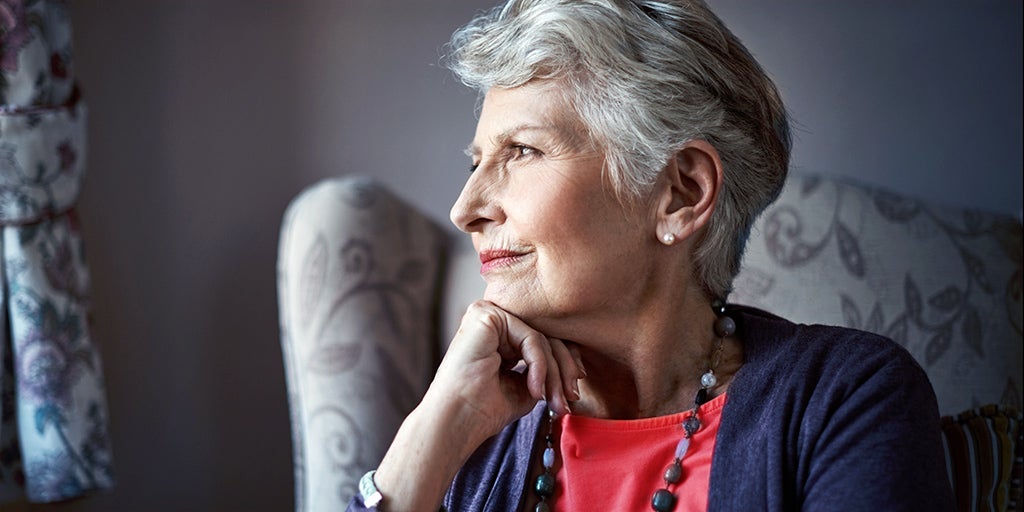 Elderly woman looking out of a window pondering upon life