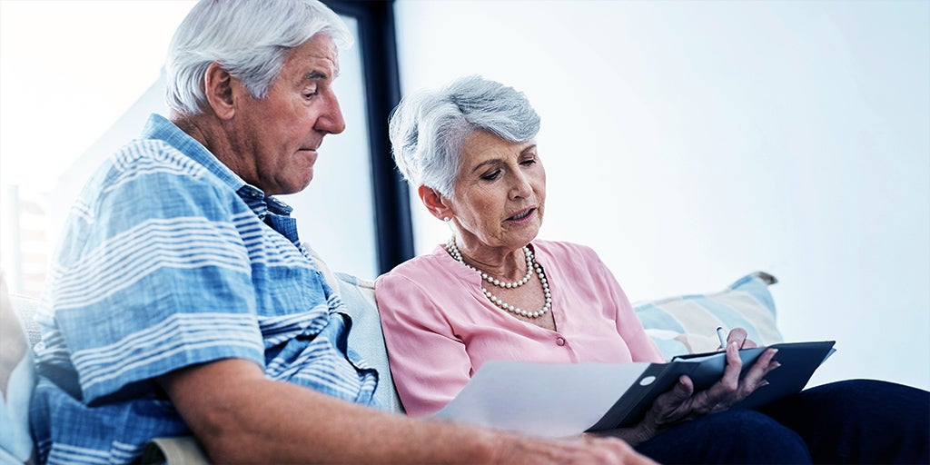 Elderly couple sitting on their sofa whilst working to put a Will in place