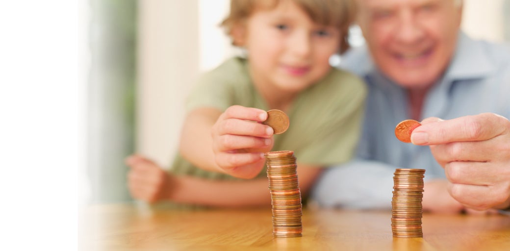Granddad and grandson smiling whilst stacking coins on a table