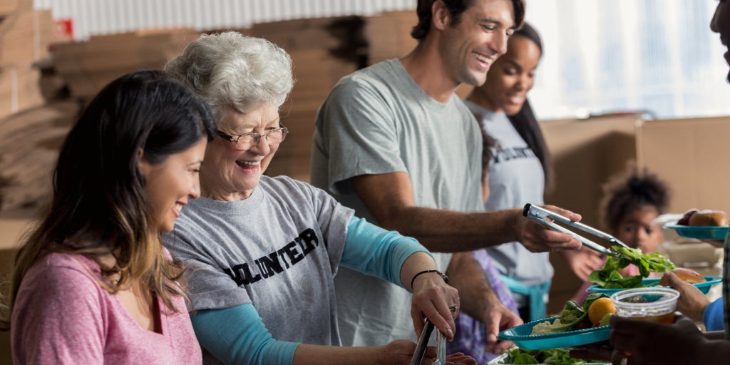 Elderly woman smiling as she helps out at a charity food bank