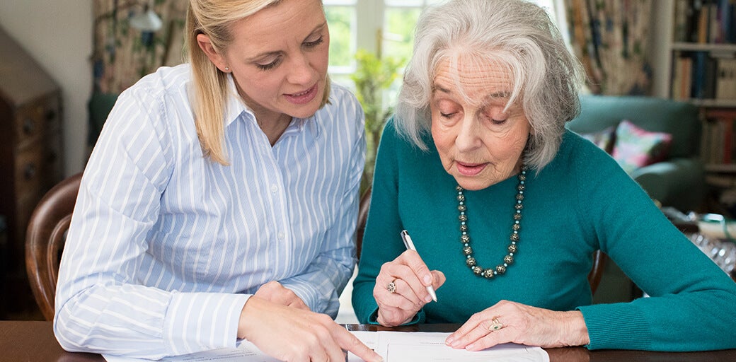 Young woman helping her mother with filling out financial documents