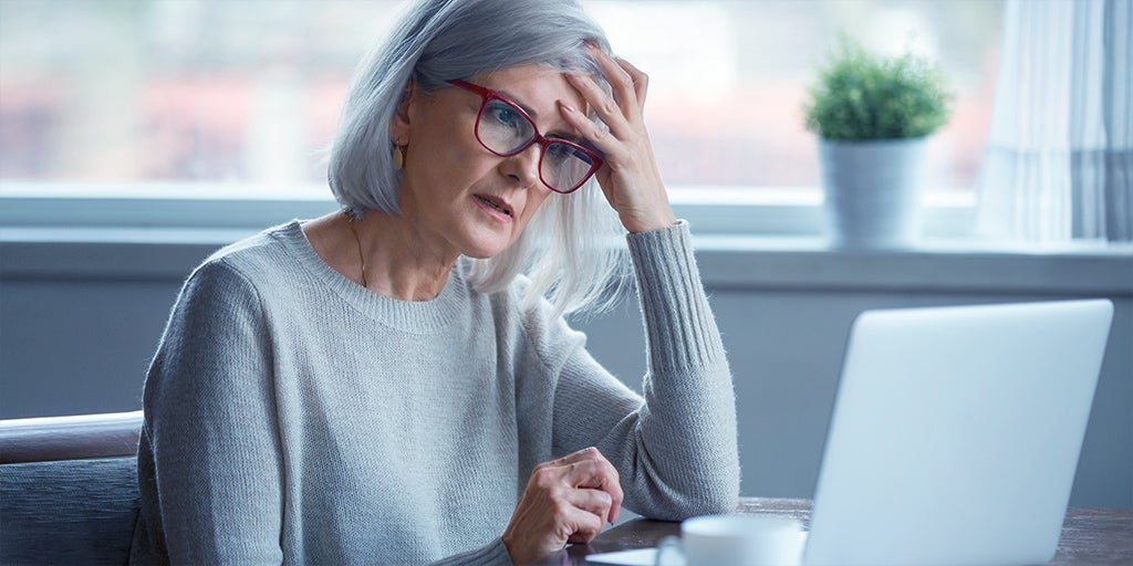 Elderly woman getting frustrated whilst buying life insurance on her laptop