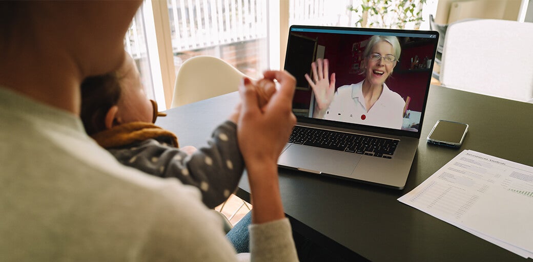 Elderly woman waving to her grandchild whilst on a video call