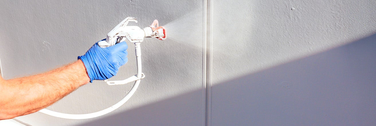 Touching up paint using a white spray gun wearing a blue protective glove