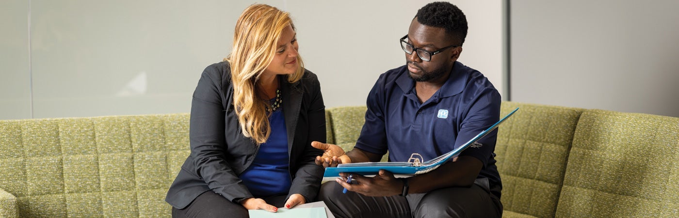 Two PPG employees discussing documents within a folder