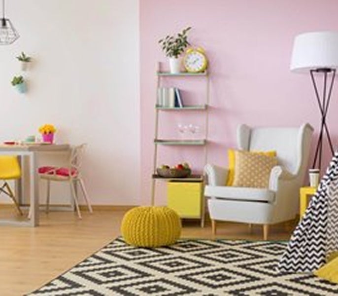 A room with a pink wall and a chair and a table