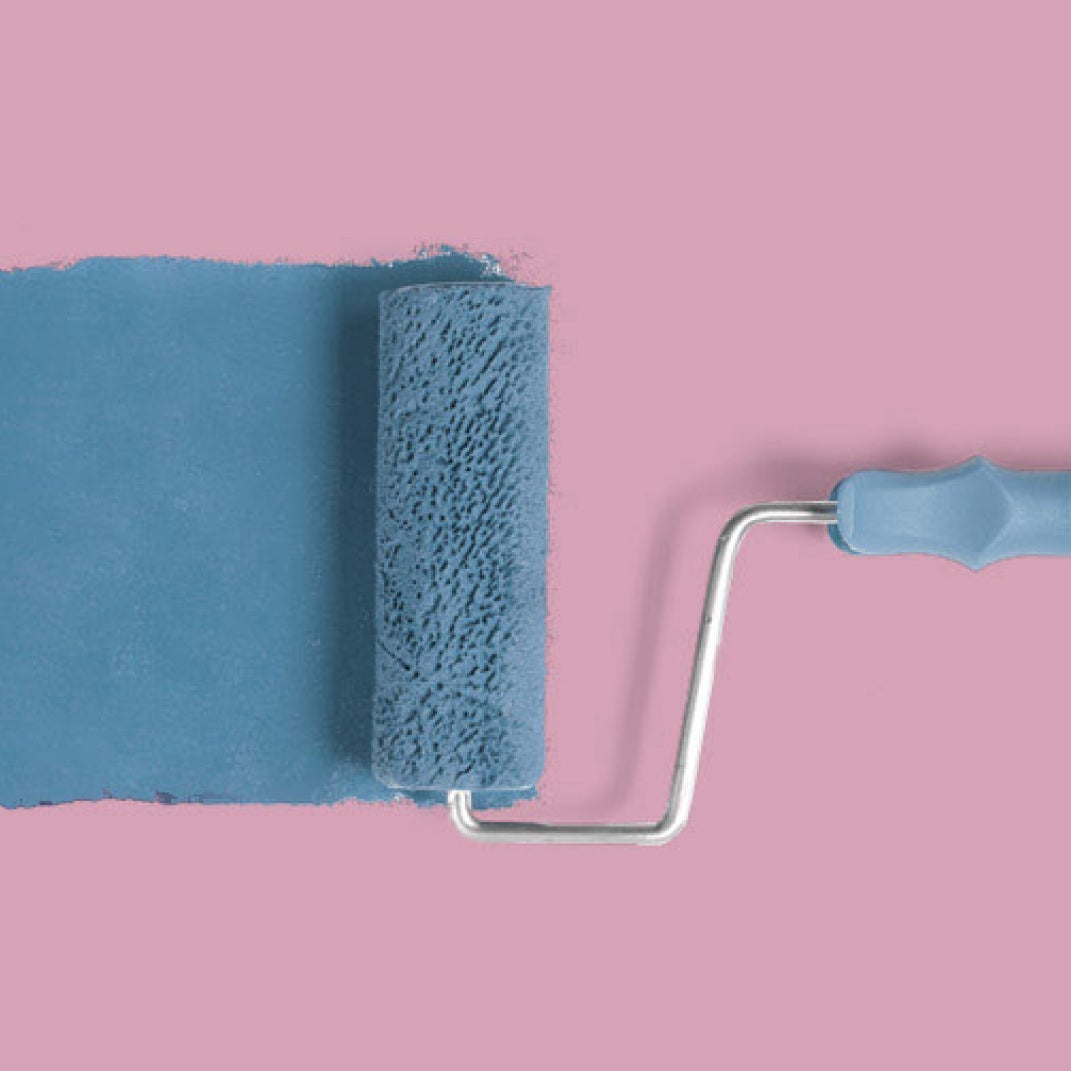 Paint roller with blue paint on pink background.