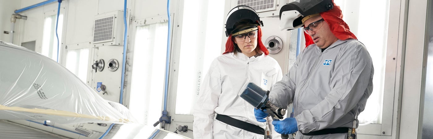 Two PPG employees in PPE inspecting spray gun