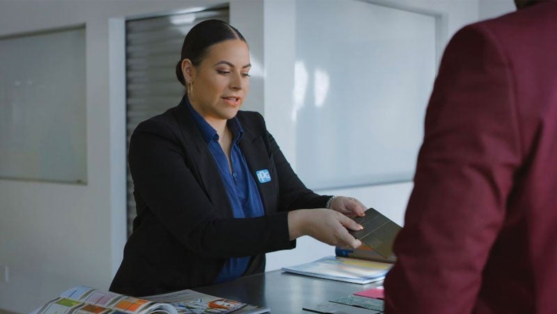 Receptionist handing over documents to a client in a modern office setting