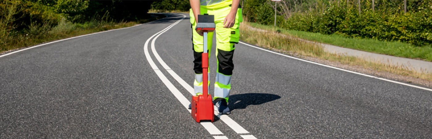 Worker using retroreflectometer on road markings