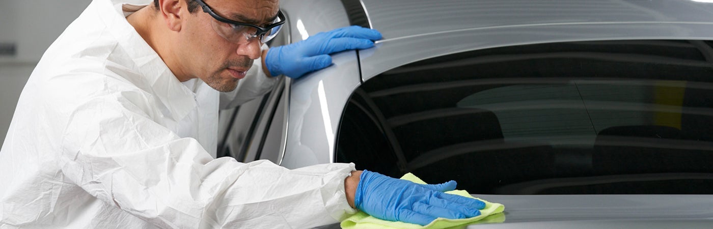 Man wearing PPE polishing car bodywork