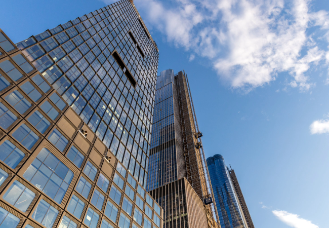 Low angle view of modern glass skyscrapers against a clear blue sky with fluffy clouds