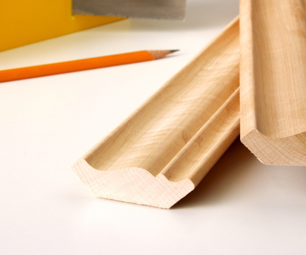 Two strips of wood finishes on a cream surface with a red pencil