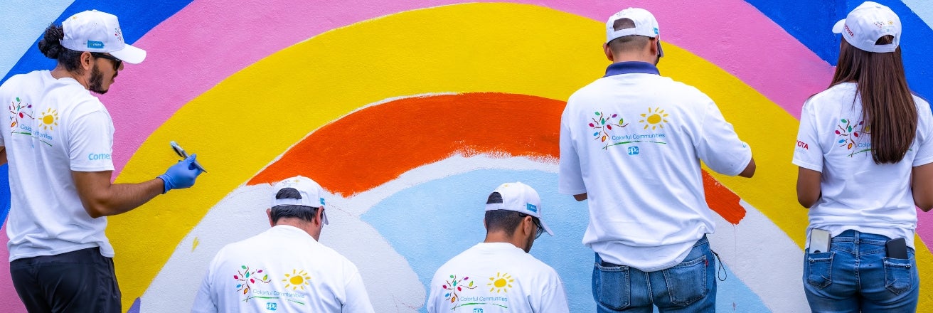 A group of volunteers painting a rainbow on a wall