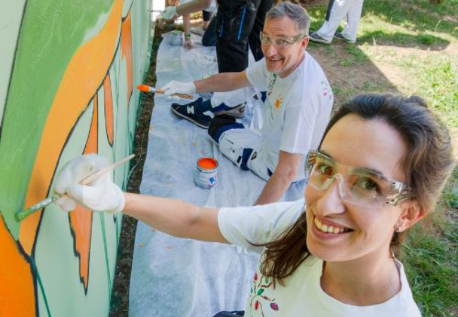 Volunteers painting wall mural in Rolle, Switzerland