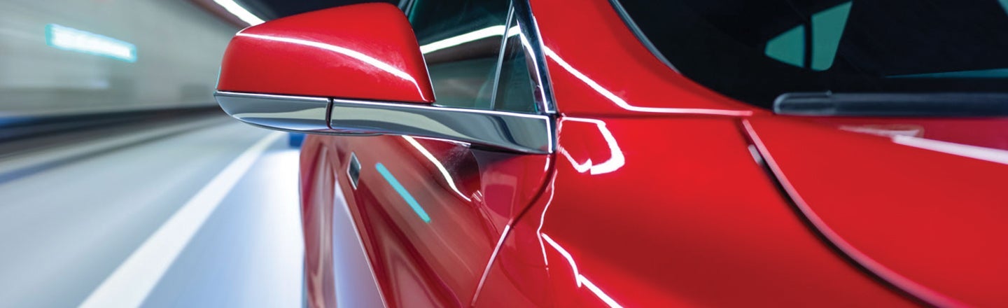 Close-up of red car wing mirror and side panel