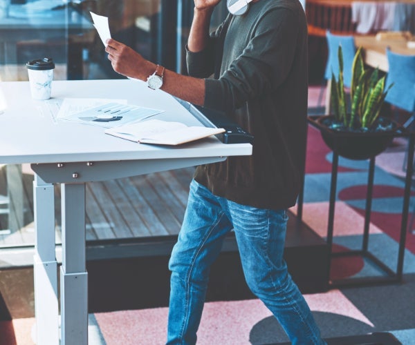 Stand up desk with a person displaying paperwork and a takeaway coffee cup