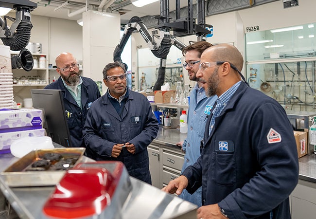 Four colleagues in lab wearing PPE whilst demonstrating new technology