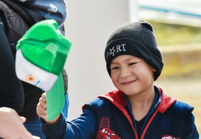 Child smiling and holding a hat