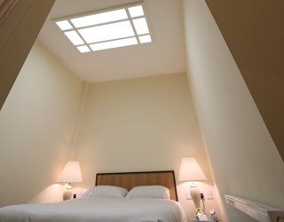 A bed with a skylight in the ceiling