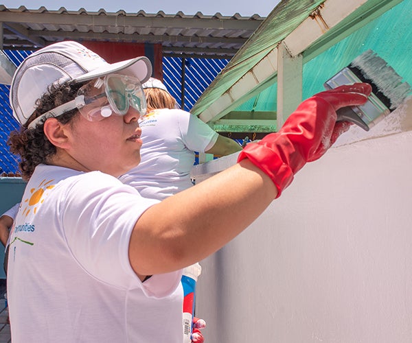 Volunteer painting building as part of Colorful Communities project