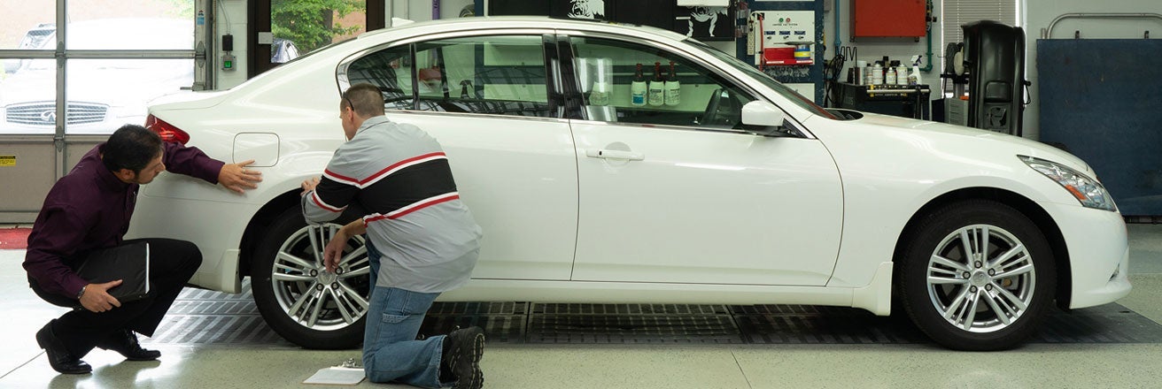 Workers examining car bodywork