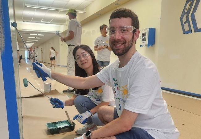 Volunteers painting blue wall at school