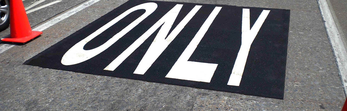 Black and white road marking saying the word "only"