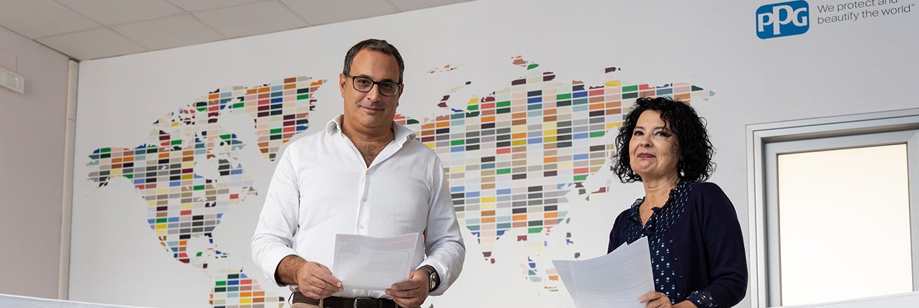 Two PPG employees stood infront of map made of colour swatches
