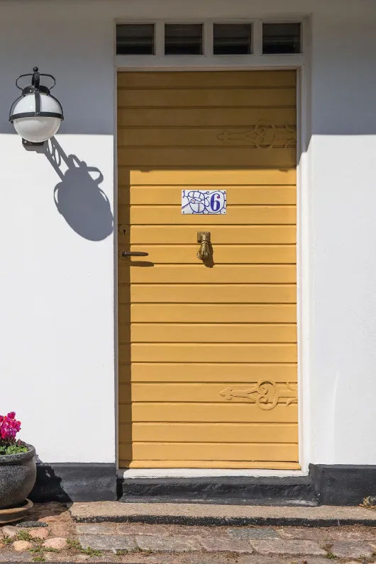 Gulmålad ytterdörr till vit putsad fasad