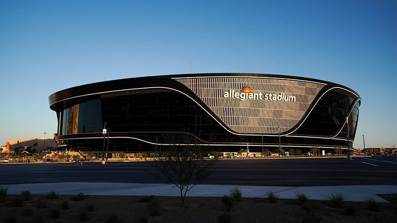 Exterior view of Allegiant Stadium, featuring its distinct curved architecture and black glass facade, captured in daylight