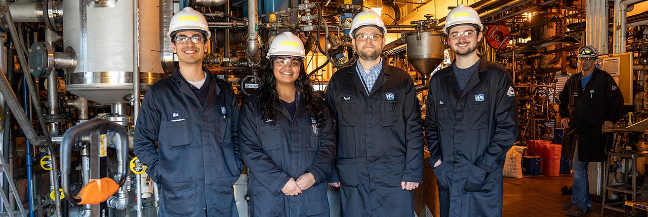 Four PPG workers in PPE in factory containing pipework
