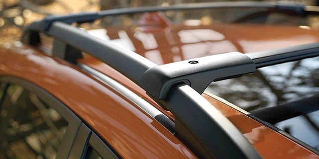 Close-up view of a modern car roof rack mounted on an orange vehicle, highlighting the sturdy design and sleek finish.