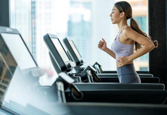 Young woman running on treadmill at a gym